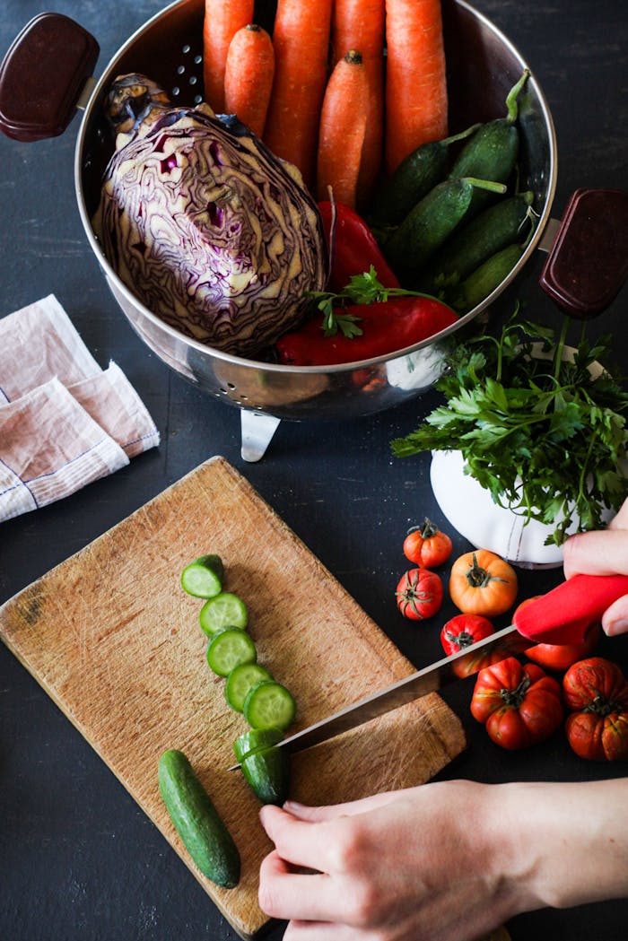 Sliced cucumbers and fresh veggies on a cutting board for healthy meal prep.